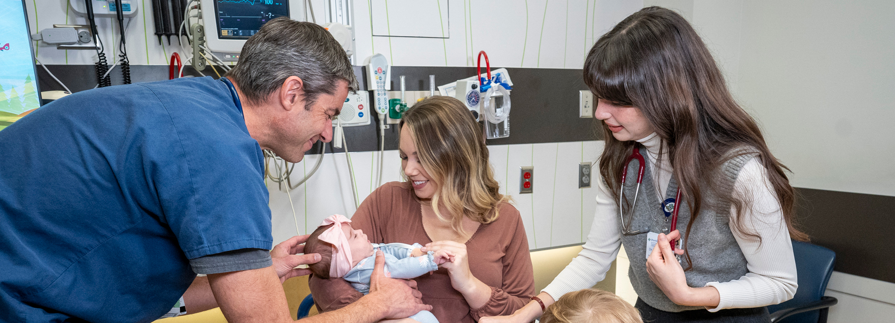 Doctor and resident helping mother and child in a hospital room.