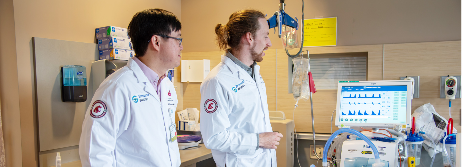 Two fellows standing next to a mechanical ventilator.