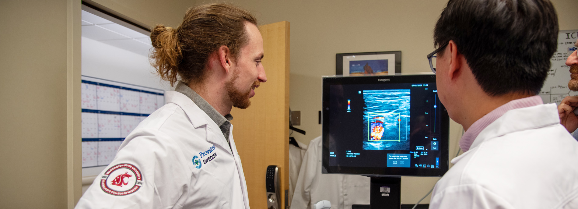 Two fellows looking at a monitor showing results of a scan.