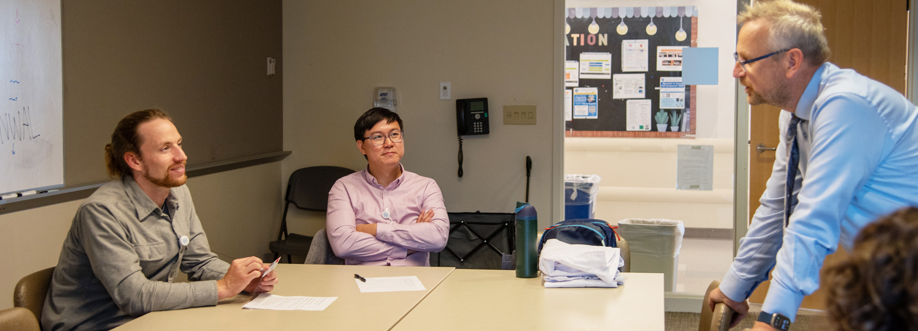 Two fellows taking with a doctor in the conference room.