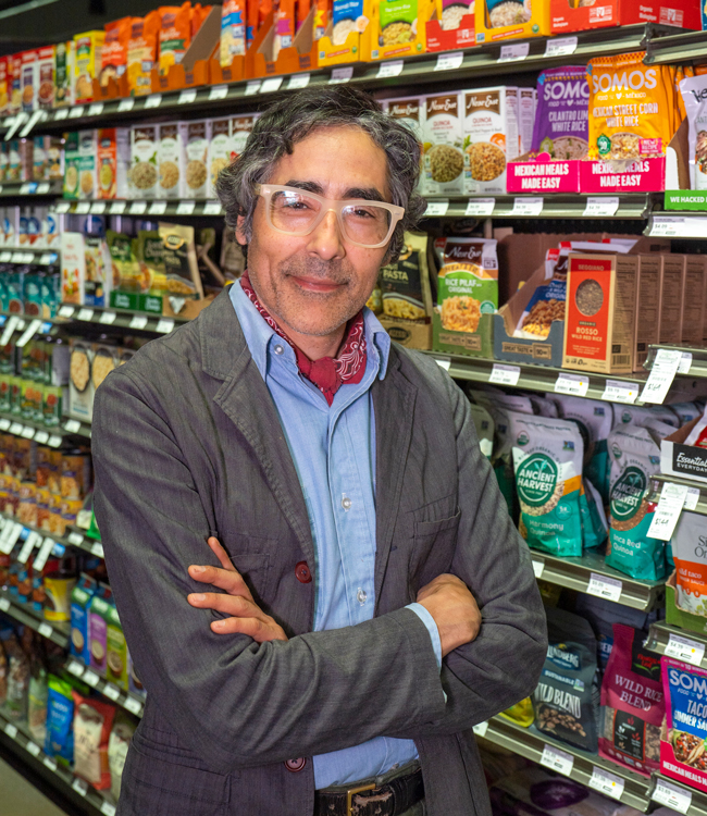 Pablo Monsivais standing inside a market in front of a shelf of packaged food.