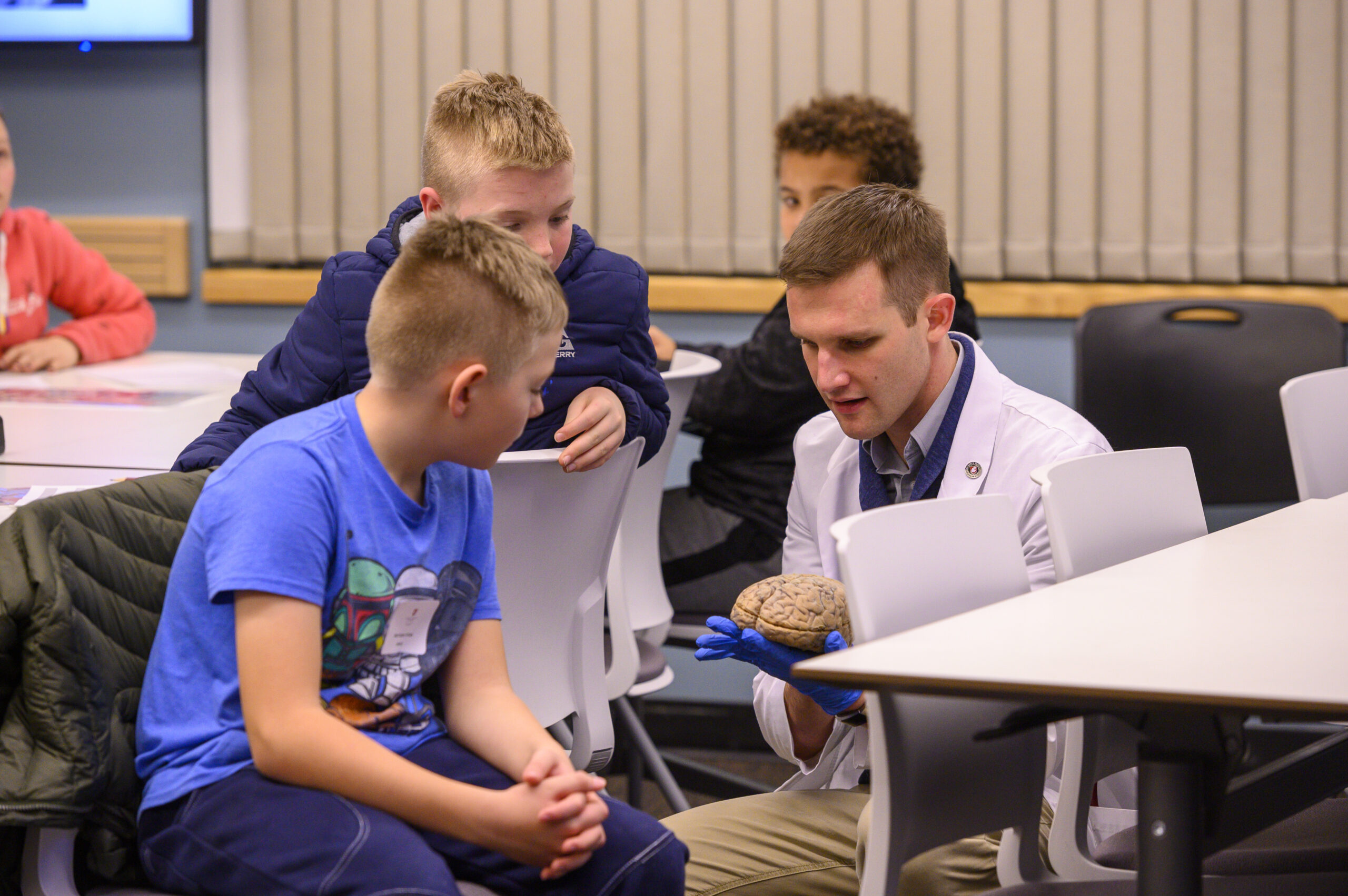 Medical student showing a brain model to high school students