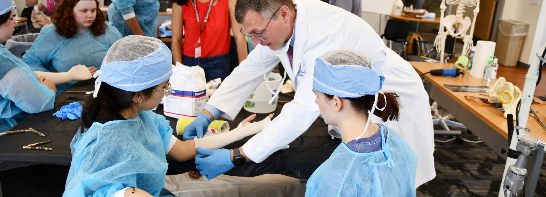 Doctor showing high school students how to cast a hand