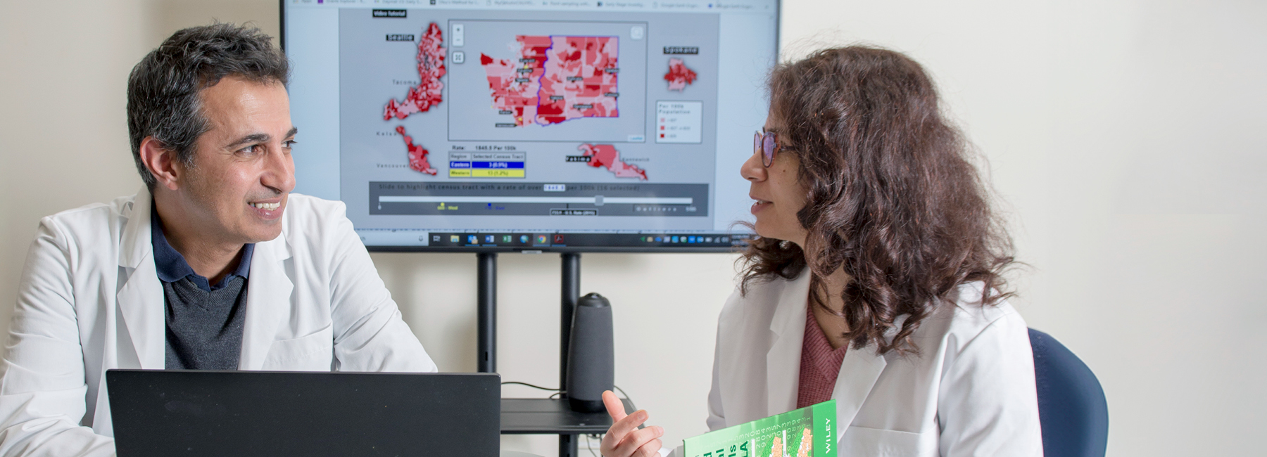 Faculty talking to student with a tv in the background