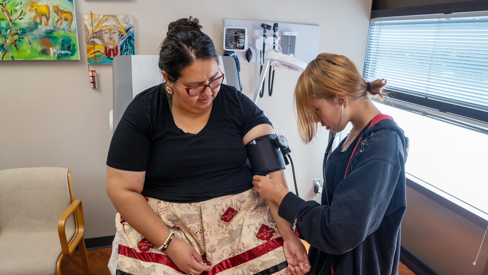 Student taking the blood pressure of a patient in a clinic room.
