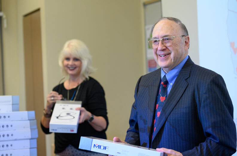 Donor Sam Selinger, MD handing out stethoscopes to MD students.