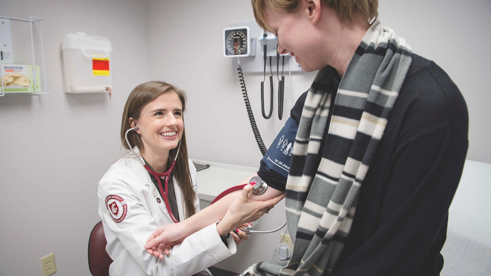 Medical student checking blood pressure of a standardized patient in the VCC.