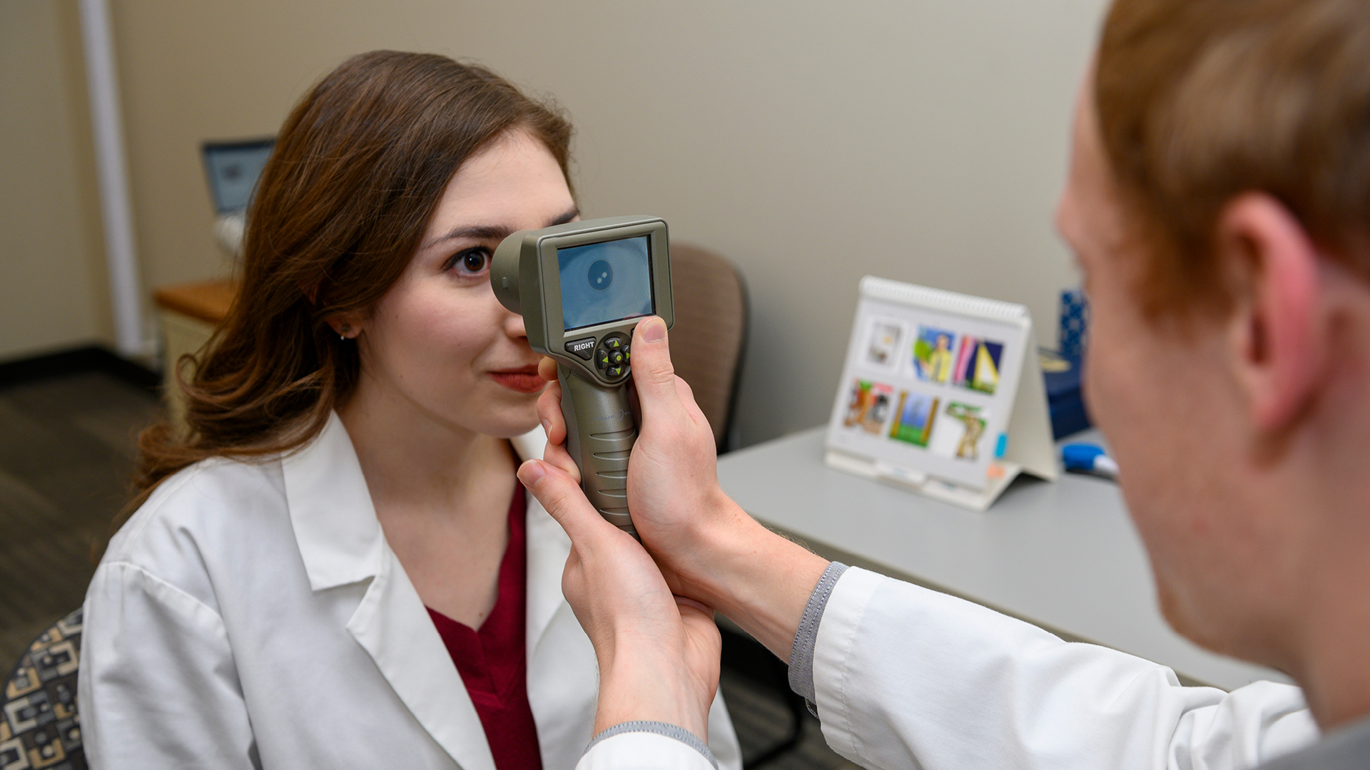 Graduate student testing eye of another student. 