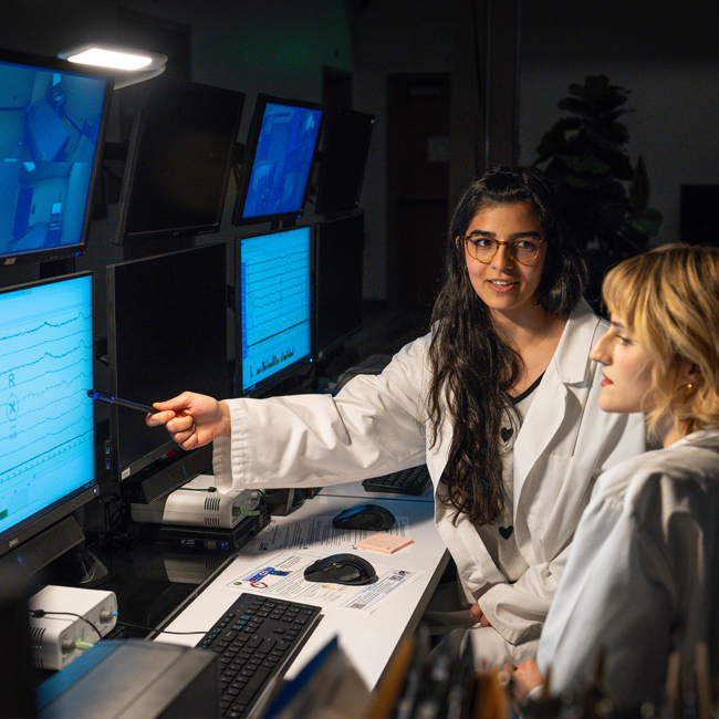 Two researchers reviewing monitors.