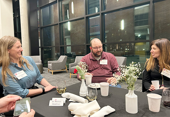 Poppy Gardiner, Travis Denton and Sabrina Paganoni taking at the dinner table.