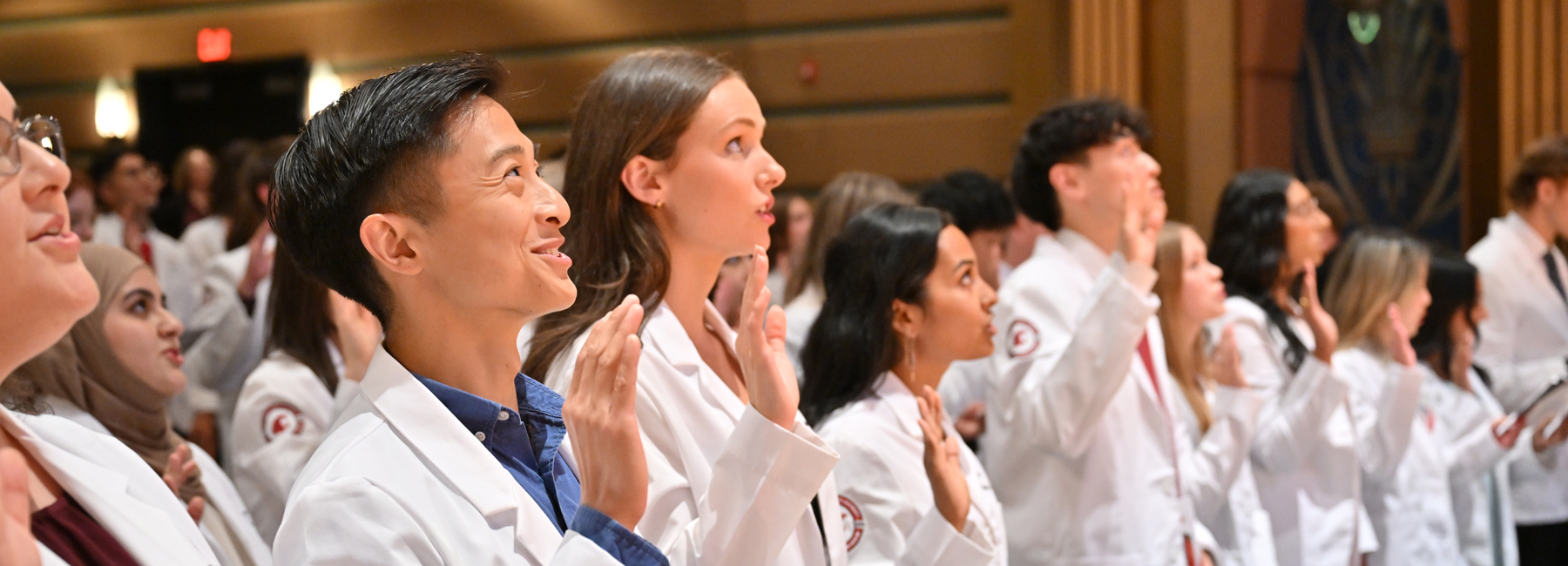 A group of MD students from the class of 2029 at white coat ceremony reciting their oath.