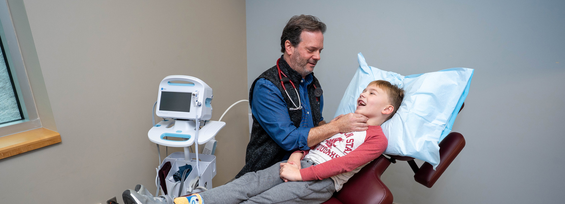 Doctor checking a child's throat as the child lies on the exam table.