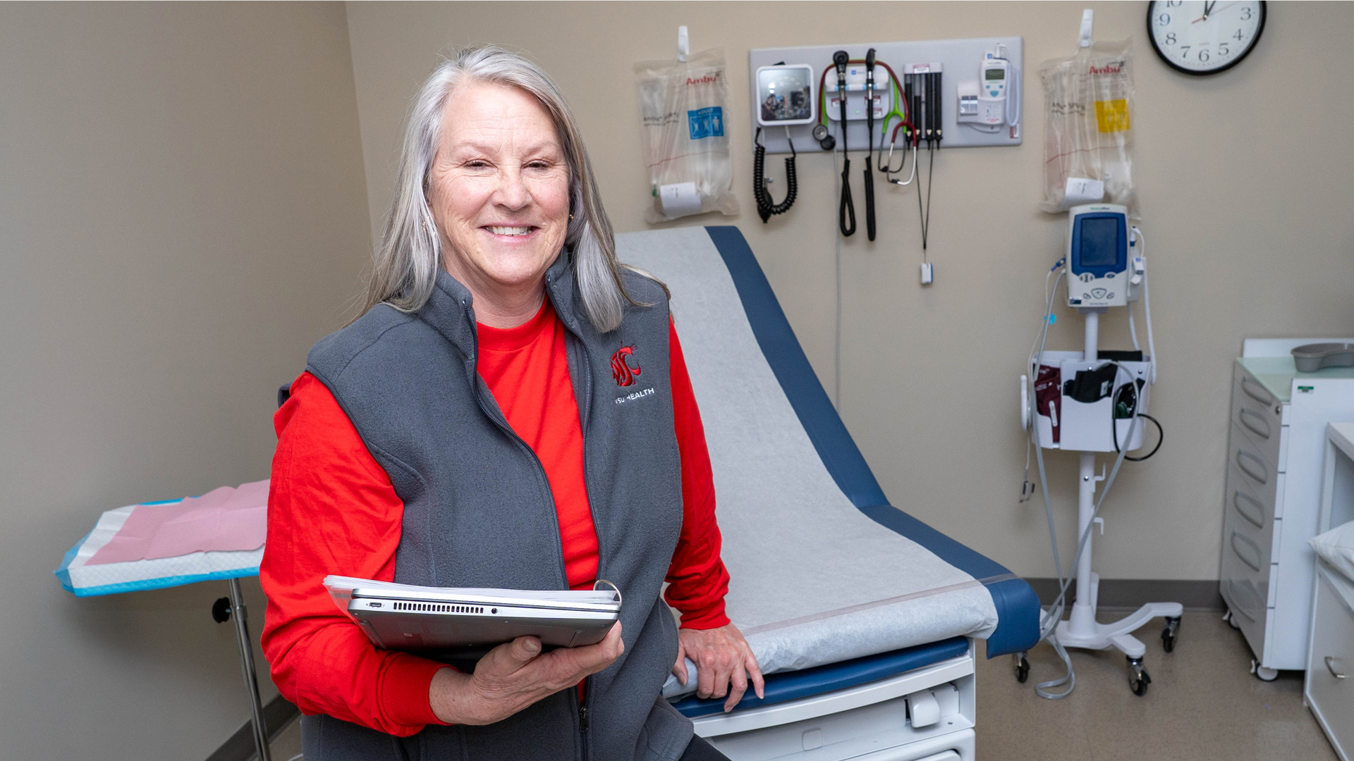 Nurse smiling, holding a chart.