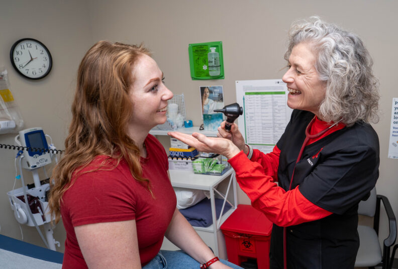 Nurse getting ready to check the throat of a student patient.