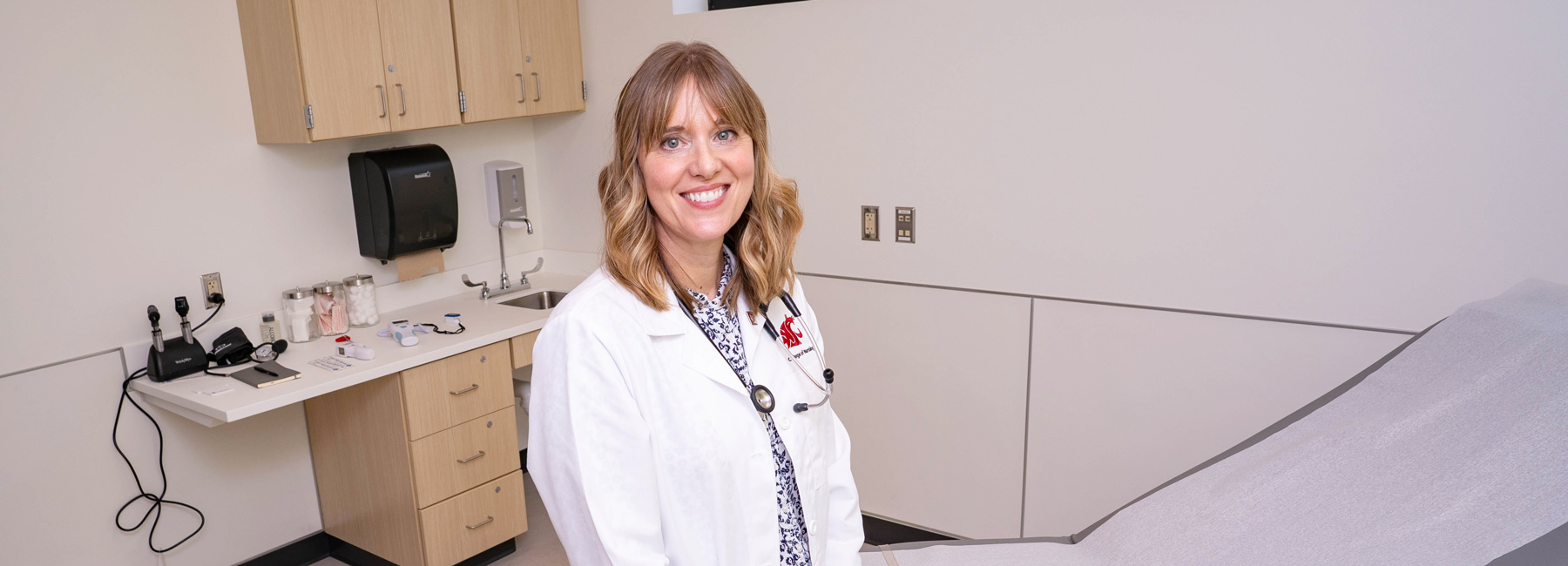 Nurse standing in the exam room smiling.