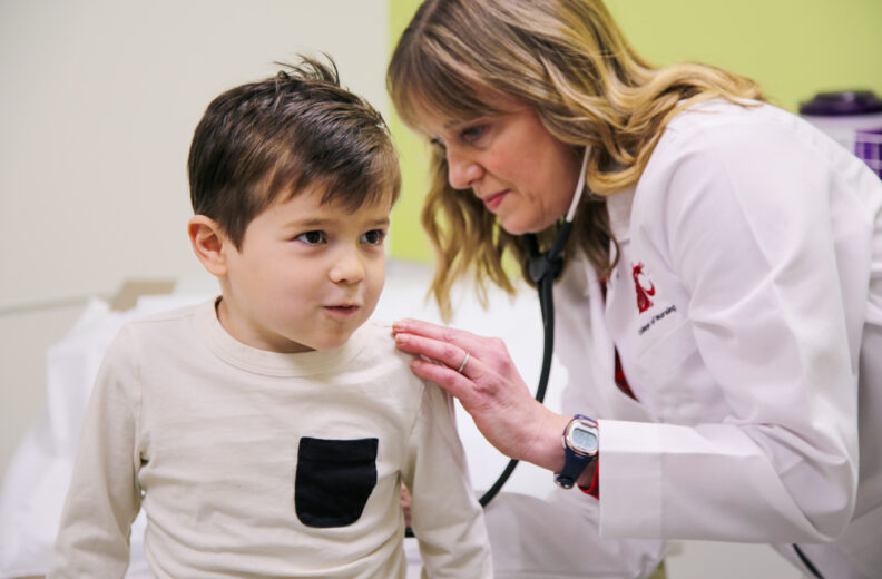 Nursing listening to breathing of a child in an exam room at the clinic.
