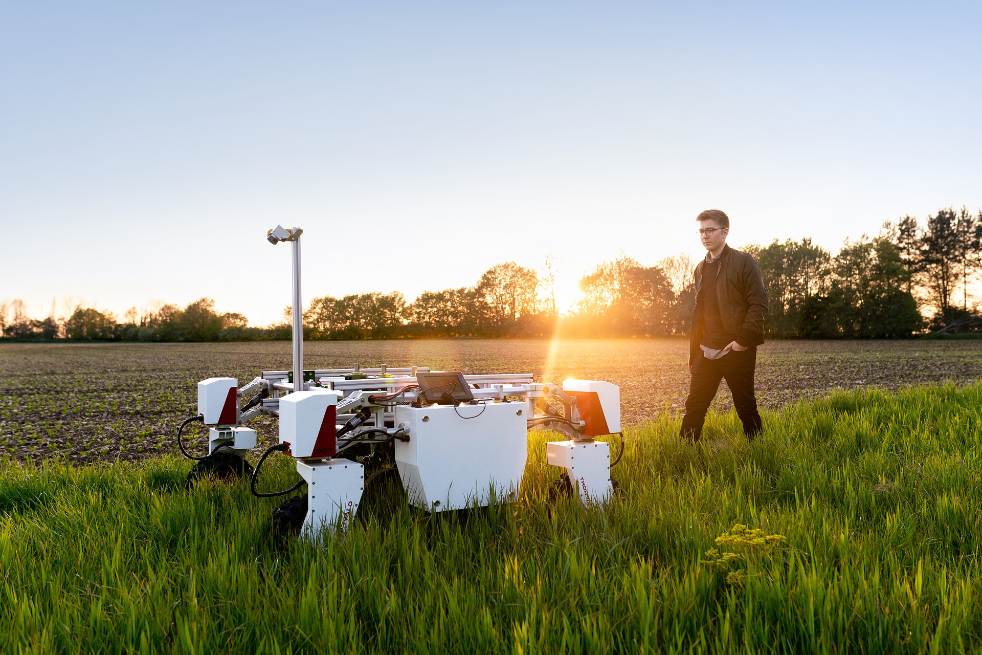 A mechanical engineering student works with an agricultural drone in a field.