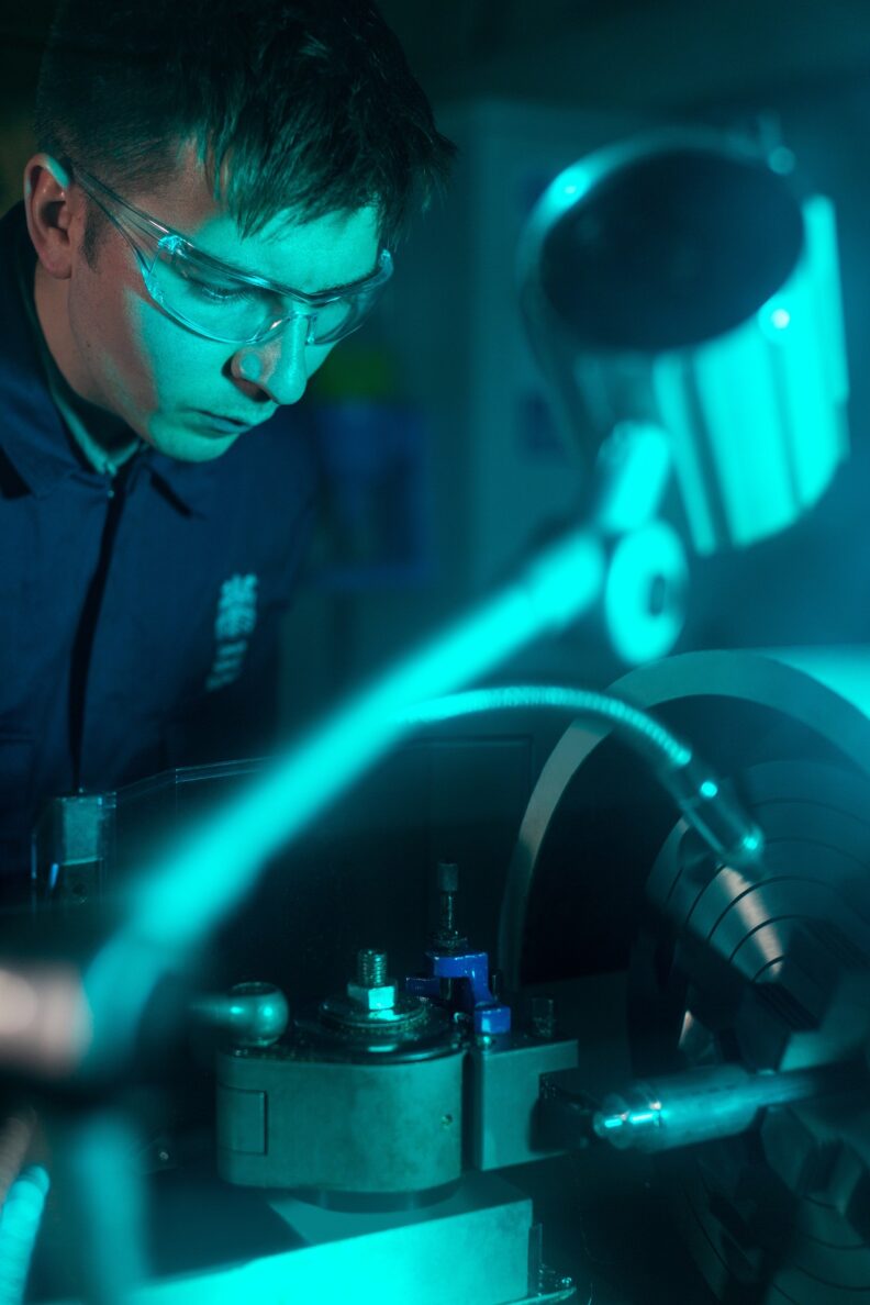 Student Engineer works on equipment in a darkened lab.