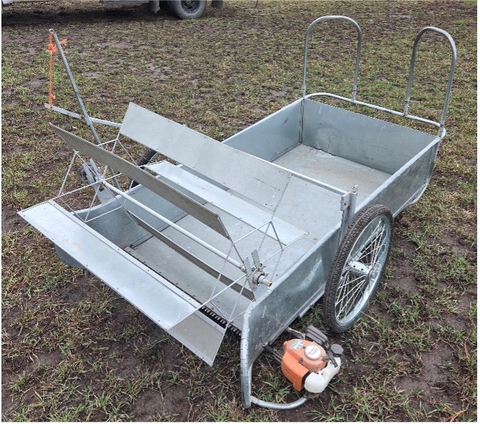 Metal swather sitting on cut grass.