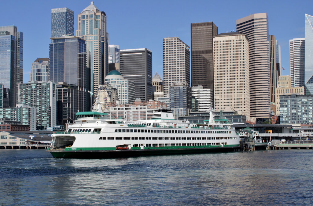 A ferry at a dock in downtown Seattle with several tall buildings in the background.