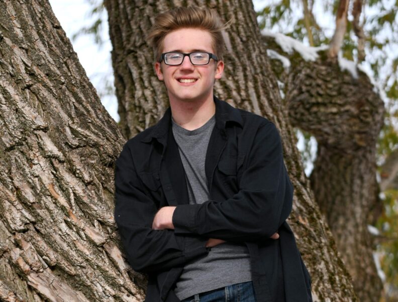 Murrow college student leaning on tree