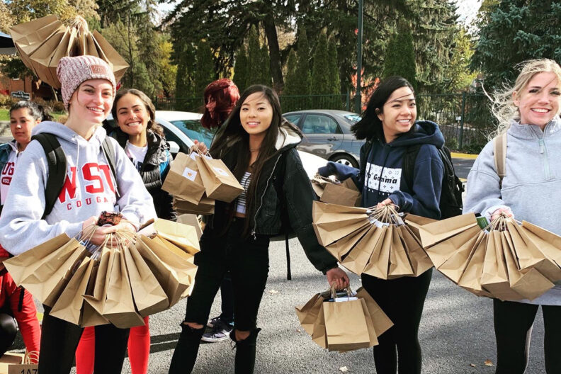 Students from Grassroots on Greek Row holding brown handout bags