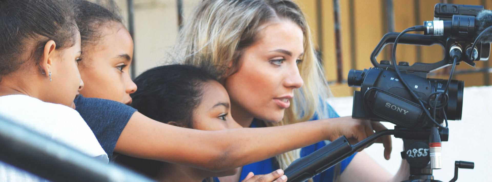 Murrow student looking through video camera with children.