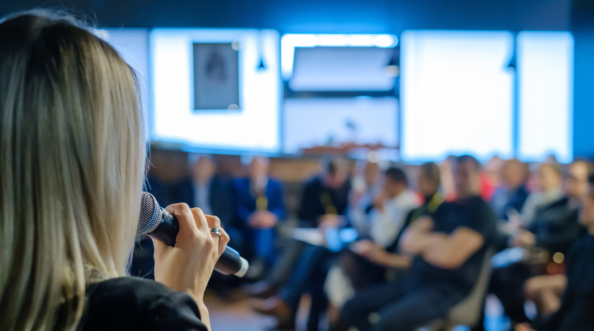 woman speaking into a microphone in front of an audience