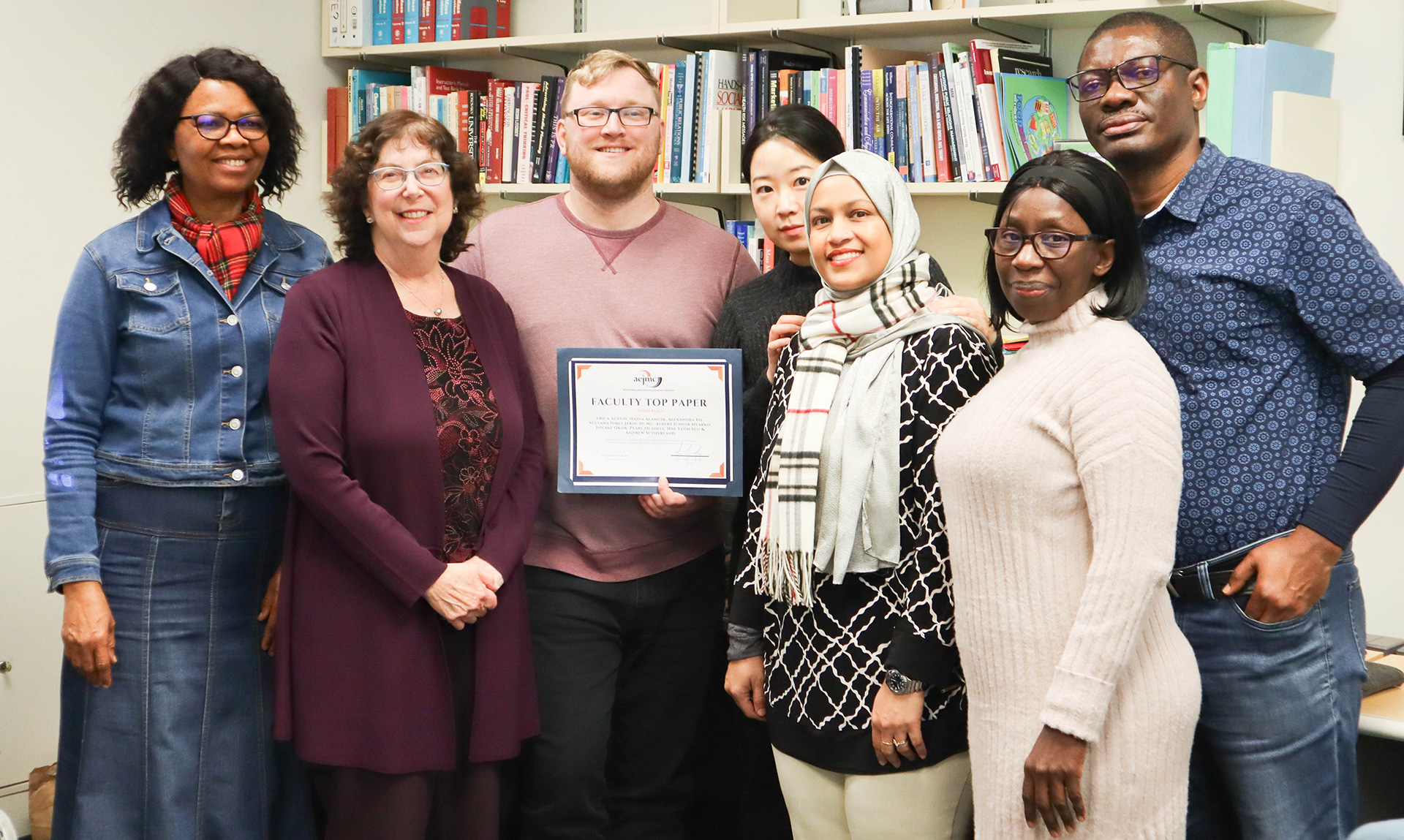 Graduate students holding up a Faculty Top Paper award