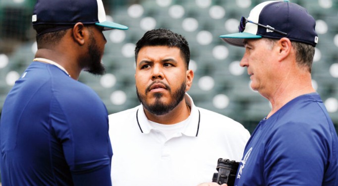 Jose Alfredo "Freddy" Llanos talking with two Seattle Mariners coaches and/or players.