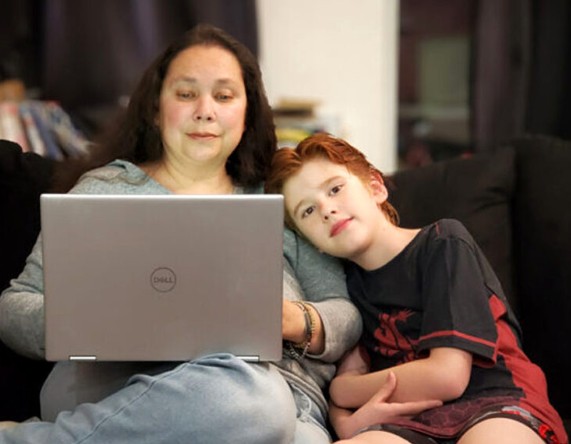 Aunjelique Andersen works on her computer next to her son (photo courtesy of Aunjelique Andersen).