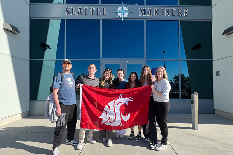 Students holding up a WSU flag outside the Seattle Mariners building