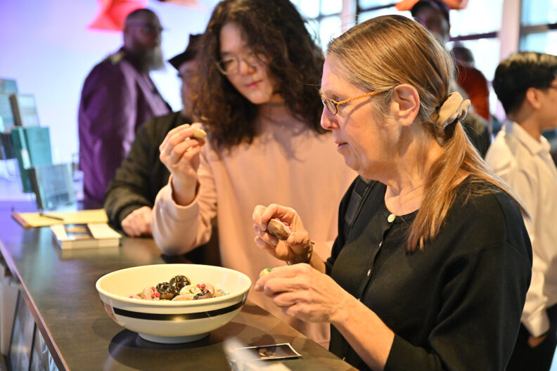 Two people examine small ceramic bundt cakes in a bowl