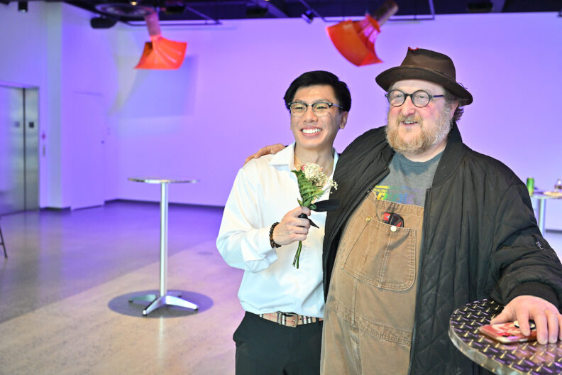 Allen Vu and another person holding a flower and smiling in the museum pavilion gallery.