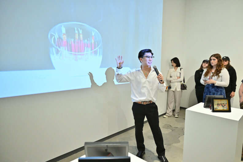 Allen Vu speaking into a microphone to a group of people in a museum art gallery.