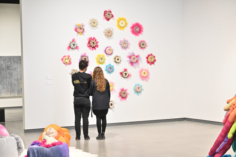 Two people viewing colorful ceramic artworks on the wall in the museum gallery.