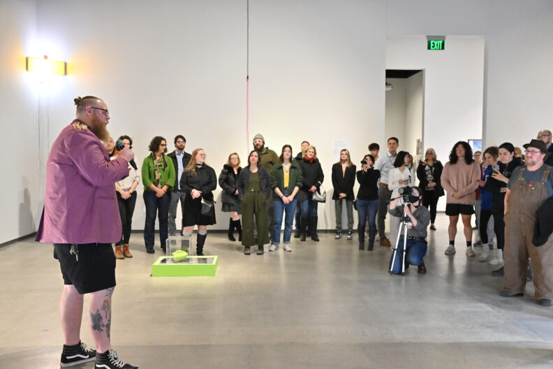 Sean Sullivan speaking in front of a crowd in a museum gallery.