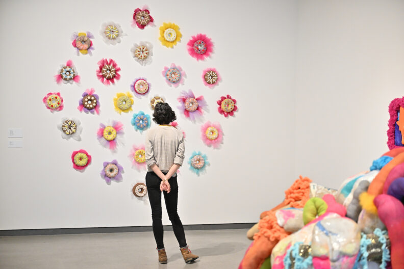 A person looks at colorful ceramic artwork on the wall in the museum gallery.