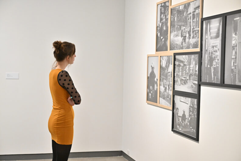 A visitor viewing framed black and white photographs on a gallery wall.