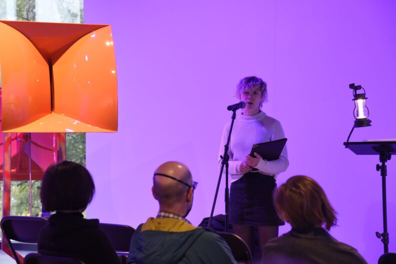 A person speaks into a microphone in front of a group of people.