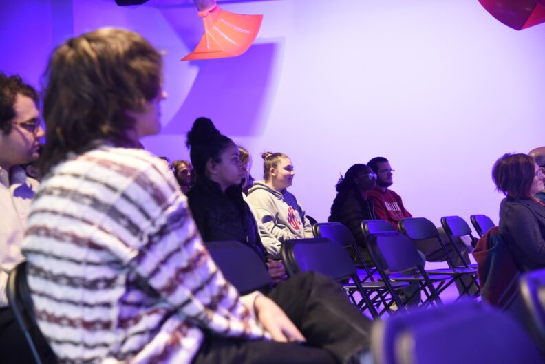 A group of people sit in an art gallery.