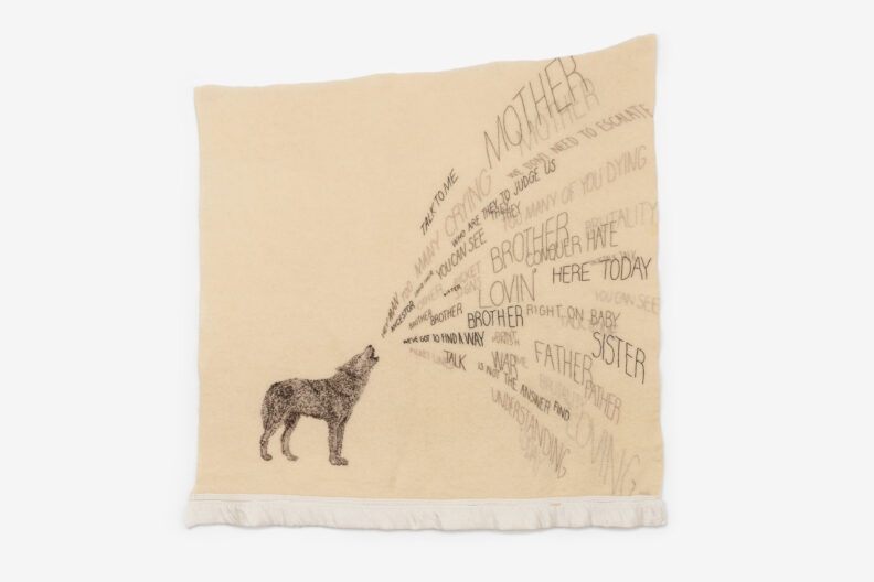 Woven cream colored wool blanket embroiderd with a wolf and a stream of words, by artist Marie Watt