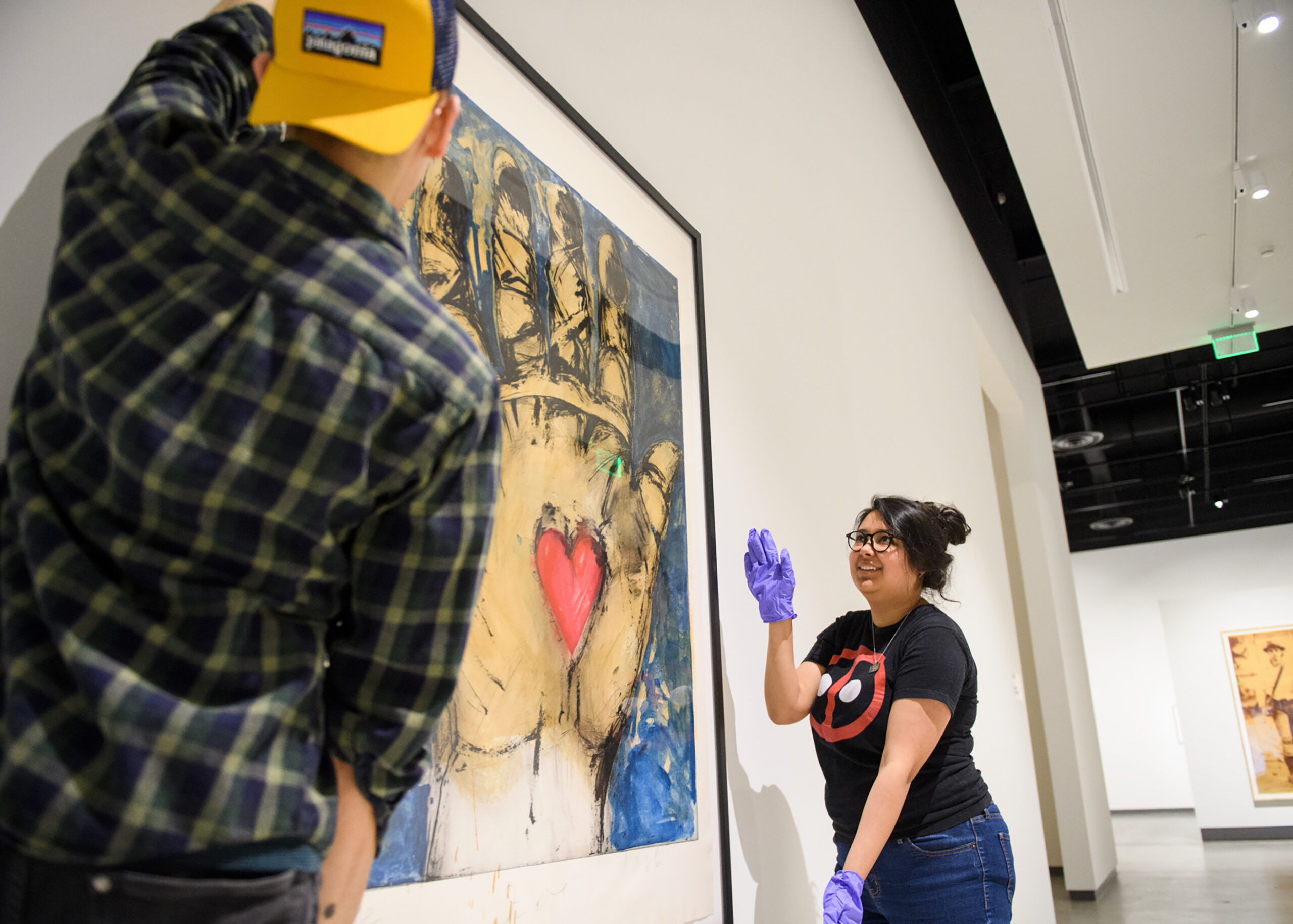Two students hang a large print in the gallery.