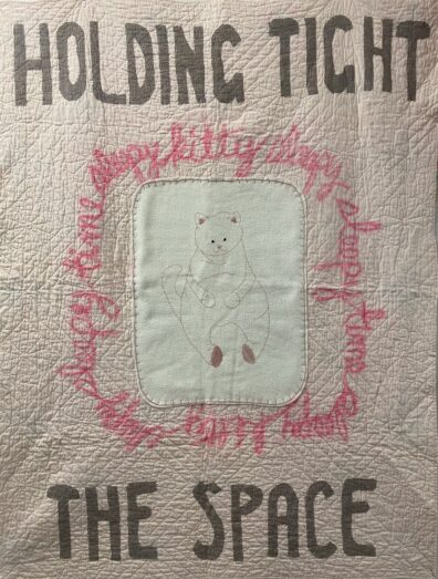 pink, brown, and cream quilt with a cat in the middle and words