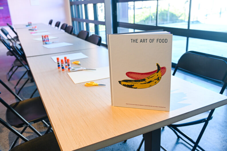 Image of tables with art supplies and book titled “Art of Food”