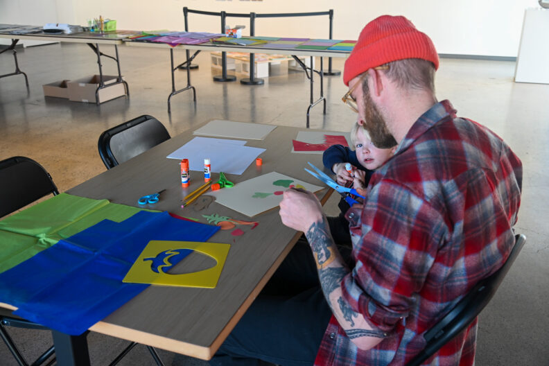 image of parent and child making collage art in the museum at a table