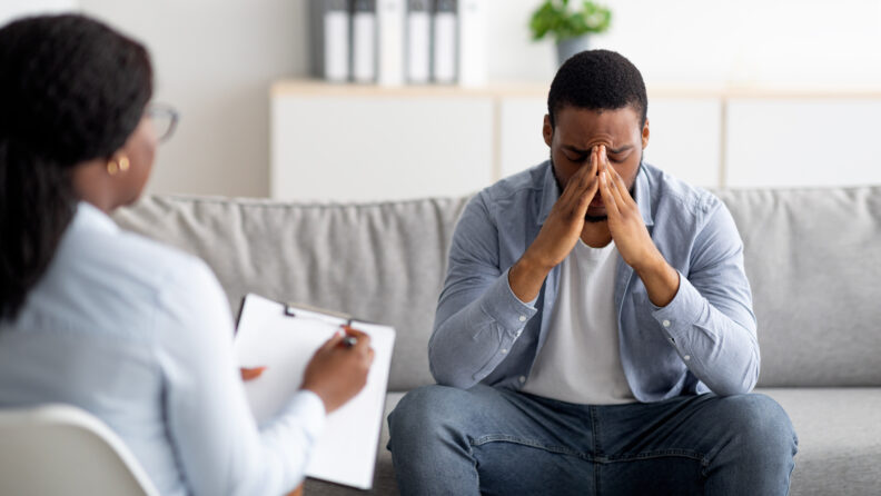 Stressed male patient meeting with therapist, receiving professional assistance