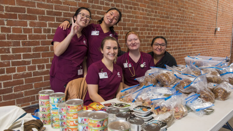 Nursing students sitting at a table covered with pet food.  