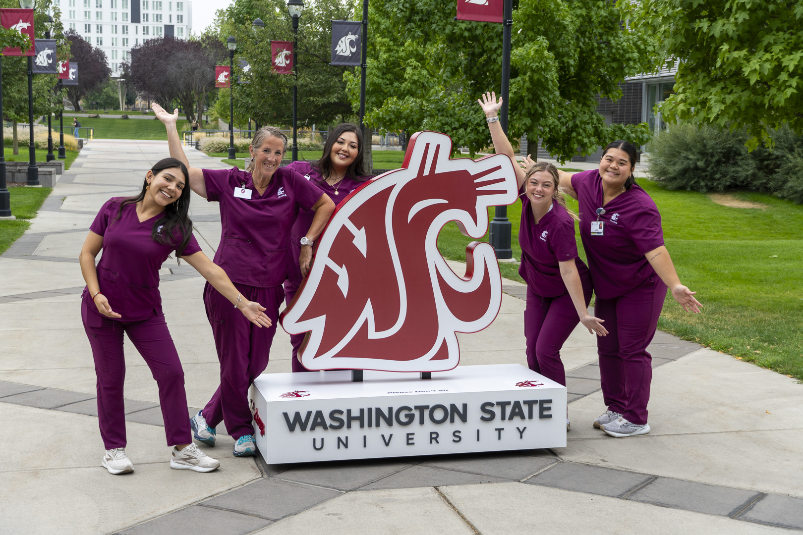 Nursing students posing around a large WSU cougar head logo statue on the WSU Spokane campus.