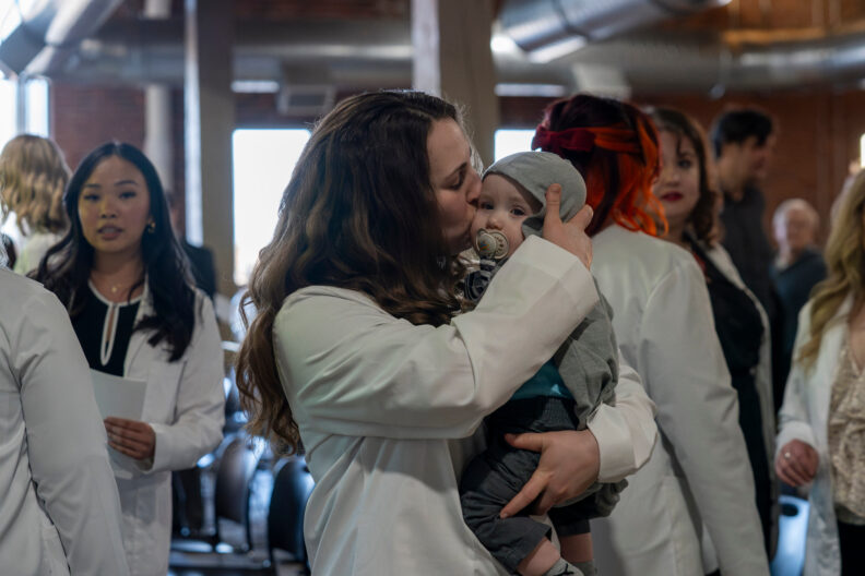 Audra Podruzny with one of her children at the 2025 DNP white coat ceremony in Spokane, WA. Photo: Cori Kogan.